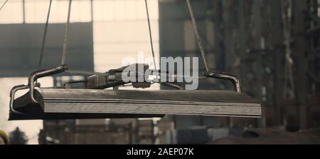 Aluminum metal new shiny steel sheets stacked with big wire rope sling onto crane block in preparation of heavy lifting in metalworking factory. Heavy Stock Photo