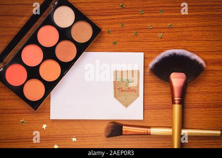 Flat lay composition with makeup products and Christmas decor on wooden background with copy space. Stock Photo