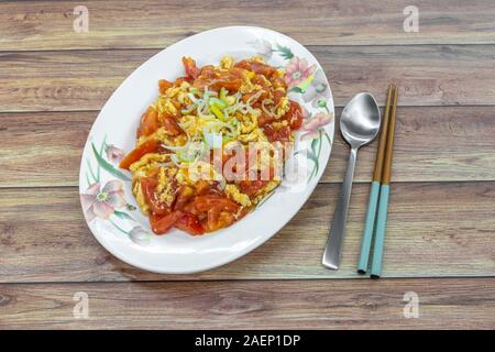 Chinese style stir fried eggs with tomatoes. Asian cooked food on table. Stock Photo
