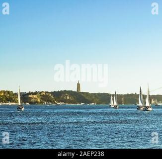 Sail boats in river Tagus with National Sanctuary of Christ the King in background. Stock Photo