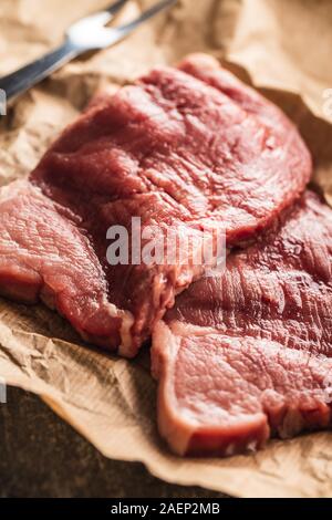 Raw veal schnitzel. Raw meat on paper. Stock Photo