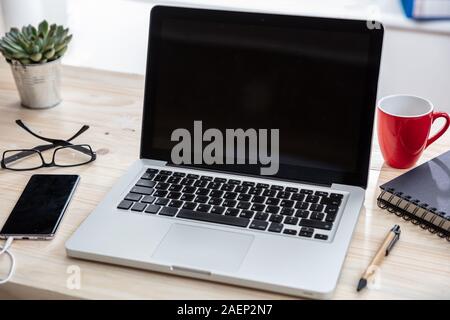Computer screen mockup. Laptop with black blank screen on a wood desk, office background, copy space Stock Photo