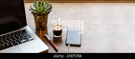 Office desk, Cozy warm workspace. Computer laptop and mobile phone on a chestnut wood table, banner, copy space Stock Photo
