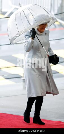 The Duchess of Cornwall uses an umbrella to shelter from the rain as she arrives for the commissioning ceremony of the Royal Navy aircraft carrier, HMS Prince of Wales, at Portsmouth Naval Base. Stock Photo