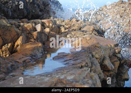 Small seaside rock-pool with sky reflection Stock Photo