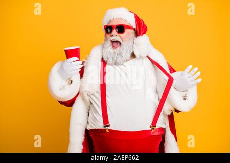Funky big belly christmas grandfather in red x-mas hat headwear visit noel party hold disposable glass cup mug with beer feel crazy isolated over Stock Photo
