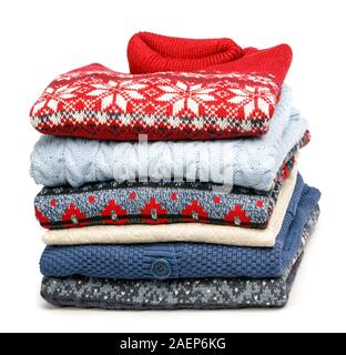 Stack of folded various knitted sweaters and pullovers in a clothes store or at a wardrobe on white background Stock Photo