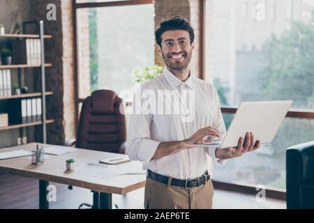 Portrait of positive confident smart middle eastern entrepreneur man hold laptop using feel success have online seminar training self-development in Stock Photo