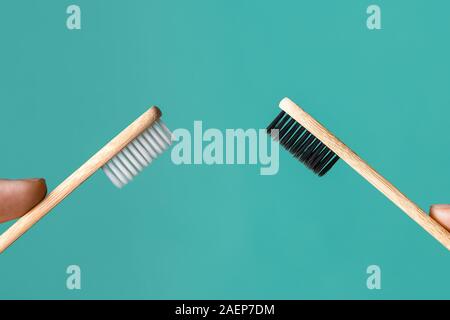 Two wooden bamboo eco friendly toothbrushes in male and female hands on aquamarine background. Dental care, family and zero waste concept. Flat lay, t Stock Photo