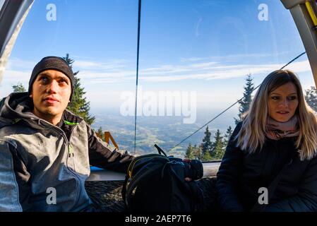 A couple in cable cart on the way to Schockl mountain. Famous travel destination Stock Photo