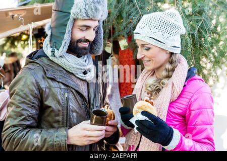 Woman and man eating and drinking on Christmas market Stock Photo
