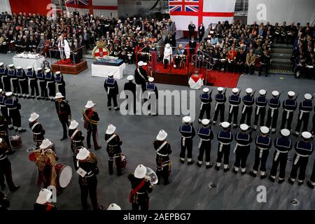 The Prince of Wales and the Duchess of Cornwall (seated centre) in the hangar, during the commissioning ceremony of the Royal Navy aircraft carrier, HMS Prince of Wales, at Portsmouth Naval Base. Stock Photo