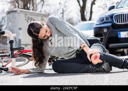 Young woman fallen down after severe injury in bicycle accident on the street Stock Photo