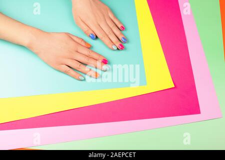 Neon manicure on different multicolored neon backgrounds. Flat lay style. Stock Photo