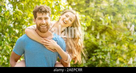 Husband is carrying his wife on his back being a reliable partner Stock Photo