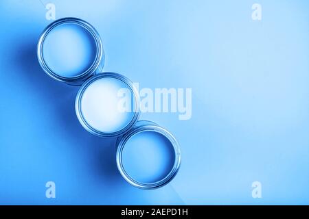 Three open cans of paint on bright symmetry background.Blue color. Place for text. Renovation concept. Stock Photo
