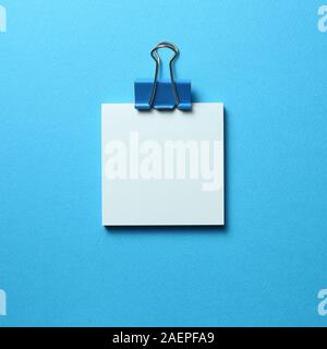 Blue memo pad sticky note and clip on blue background Stock Photo