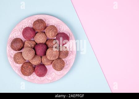 Homemade Raw Energy Balls on Vintage Plate on Blue and Pink Paper Background Stock Photo