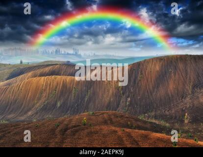 rainbow in the field. picturesque sky over a hilly field. after a thunderstorm Stock Photo