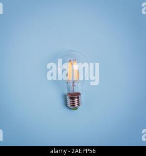 Retro electric light bulb isolated on blue background. Stock Photo