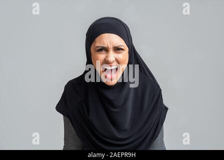 Angry muslim girl in hijab screaming loud, emotionally protesting about something Stock Photo