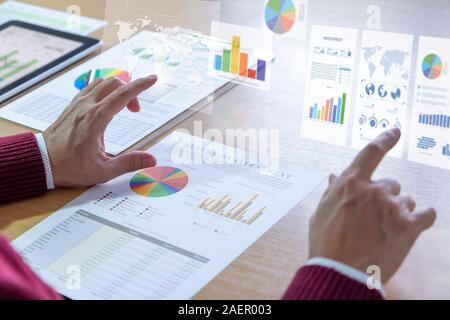 Businessman interacts with augmented reality graphics while deeply reviewing a financial report for a return on investment or investment risk analysis Stock Photo