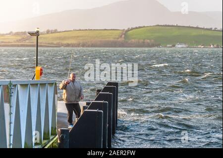 Bantry, West Cork, Ireland. Despite gale force winds causing rough seas in Bantry Harbour, this gentleman was on a pontoon fishing at high tide this afternoon.  Met Eireann issud a yellow wind warning for the whole of Ireland this morning. Credit: Andy Gibson/Alamy Live News. Stock Photo