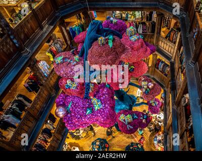 The "Tree of Liberty" Christmas display in the Liberty store, London. A Pink and Teal 8m tall floating bonsai sculpture adorned with presents. Stock Photo