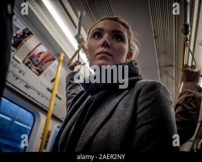 Young woman hanging on to handgrip, tube train, London, UK. Stock Photo