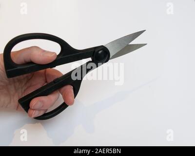 Hand holding large pair of sharp scissors Stock Photo