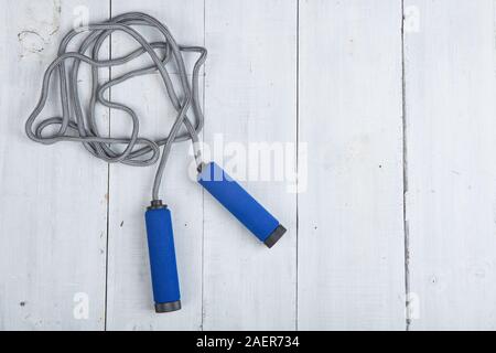 Fitness/sport and healthy lifestyle concept - Jumping/skipping rope with blue handles on white wooden background Stock Photo