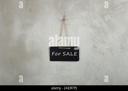 Black notice board, blackboard, chalkboard with text For Sale on grey cement wall Stock Photo