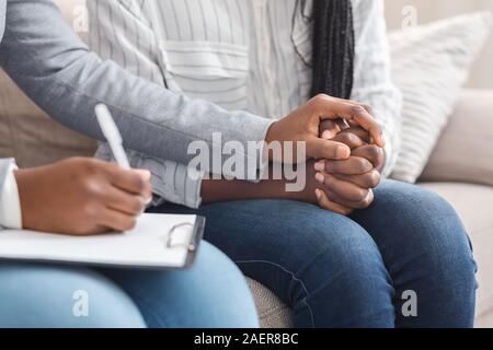 Psychologist comforting unrecognizable female patient during personal consultation in office Stock Photo