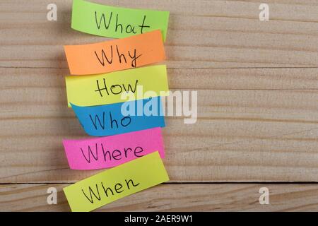 Questions - Why? What? Where? When? Why? How? on colorful stickers on wooden desk Stock Photo