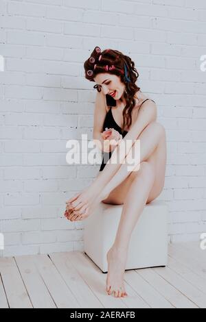 girl with hair curlers talking on the phone and paint nails Stock Photo
