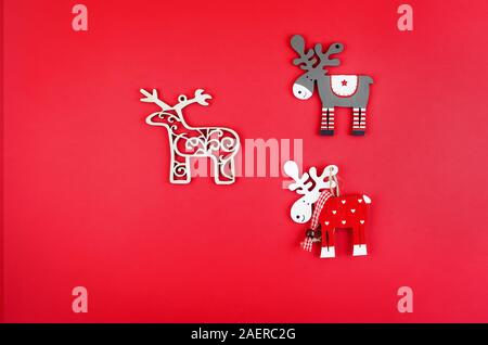 Christmas or New Year background, three decorative wooden deer on red background, holiday concept. Flat lay, top view, copy space, Template mockup gre Stock Photo