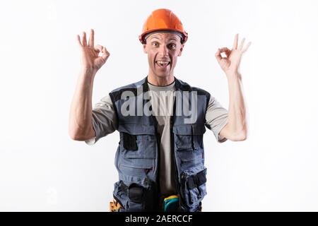 The builder shows the sign okay. In work clothes and a helmet. Stock Photo