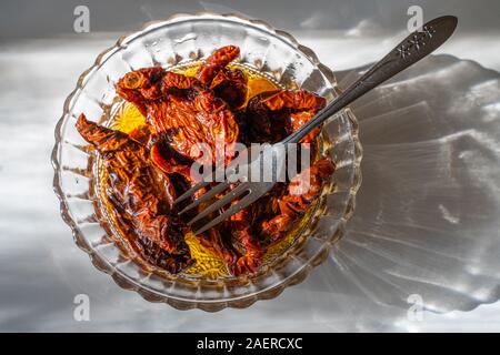 dried tomatoes and olive oil in glass bowl Stock Photo