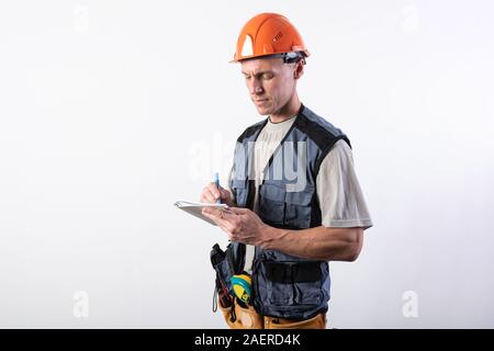 Builder with a notepad. In a helmet and a robe. Writes data. Stock Photo