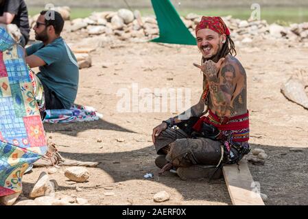 A tattooed and pirate scarf on his head looks at the camera at the psytrance Lost Theory festival in Riomalo de Abajo Stock Photo
