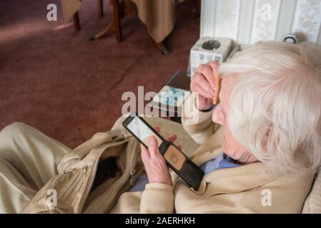 Before going out to visit her husband who is ill in hospital,the ninety year old senior lady attempts to make herself look presentable. Stock Photo