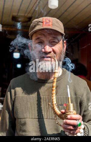 March 14, 2019: Elderly Bai ethnic minority man smoking  a pipe in Xizhou village, Yunnan, China Stock Photo