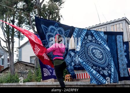 March 12, 2019: Woman doing the laundry of some typical Chinese batik in Zhoucheng, Yunnan, China Stock Photo