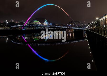 Colourful reflections in the tyne looking through the millennium bridge to the Tyne Bridge from the Quayside at night. Newcastle uk Stock Photo