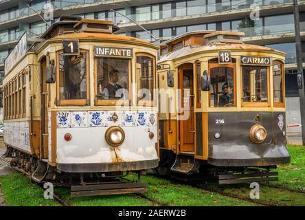 Vintage historic trams line 1 & 18 with wooden structure stand next to each other while the tram conductors chat away before they drive on in Porto Stock Photo