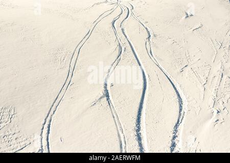 Snowy abstract off-piste skiing backround with ski and snowboard trails and tracks on new virgin powder snow. morning sunrise or evening sunset time Stock Photo