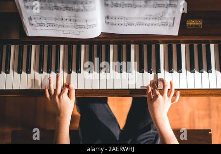 Top view of child's hands playing piano. Stock Photo