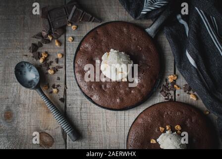 Top view of brownies with ice cream and nuts in cast iron skillets. Stock Photo