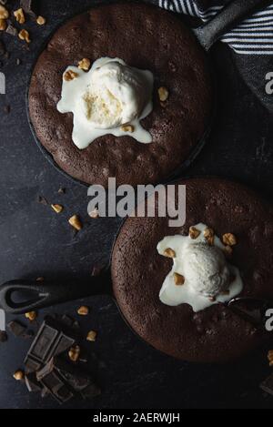 Close up of brownies with ice cream and nuts in cast iron skillets. Stock Photo