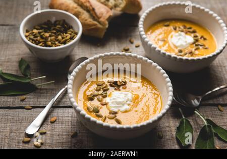 Close up of bowls of butternut squash soup on rustic wooden table. Stock Photo